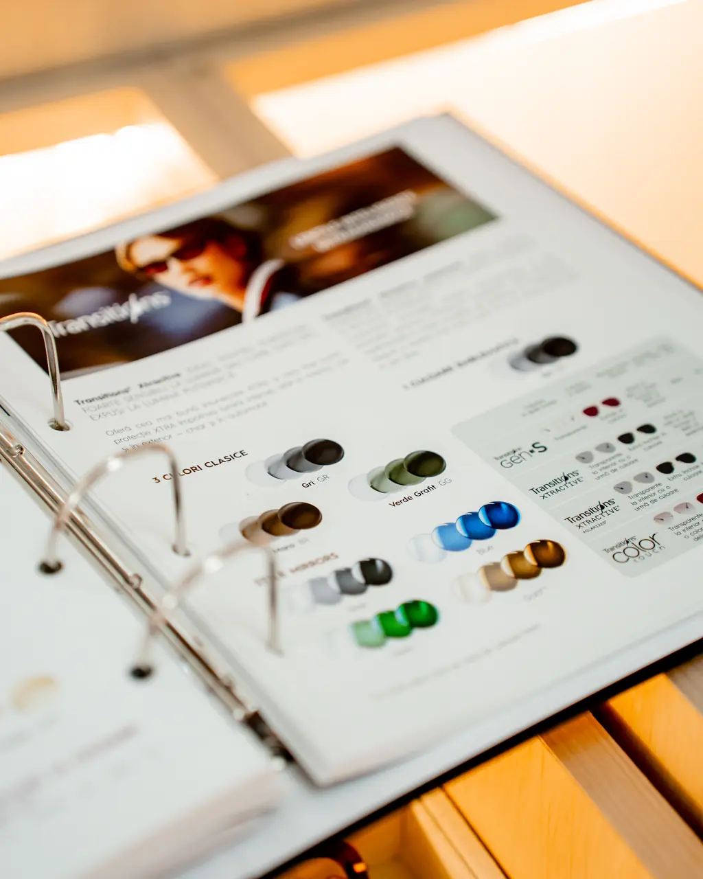 Catalog de lentile răsfoit în magazin, cu tipuri de tratamente și filtre